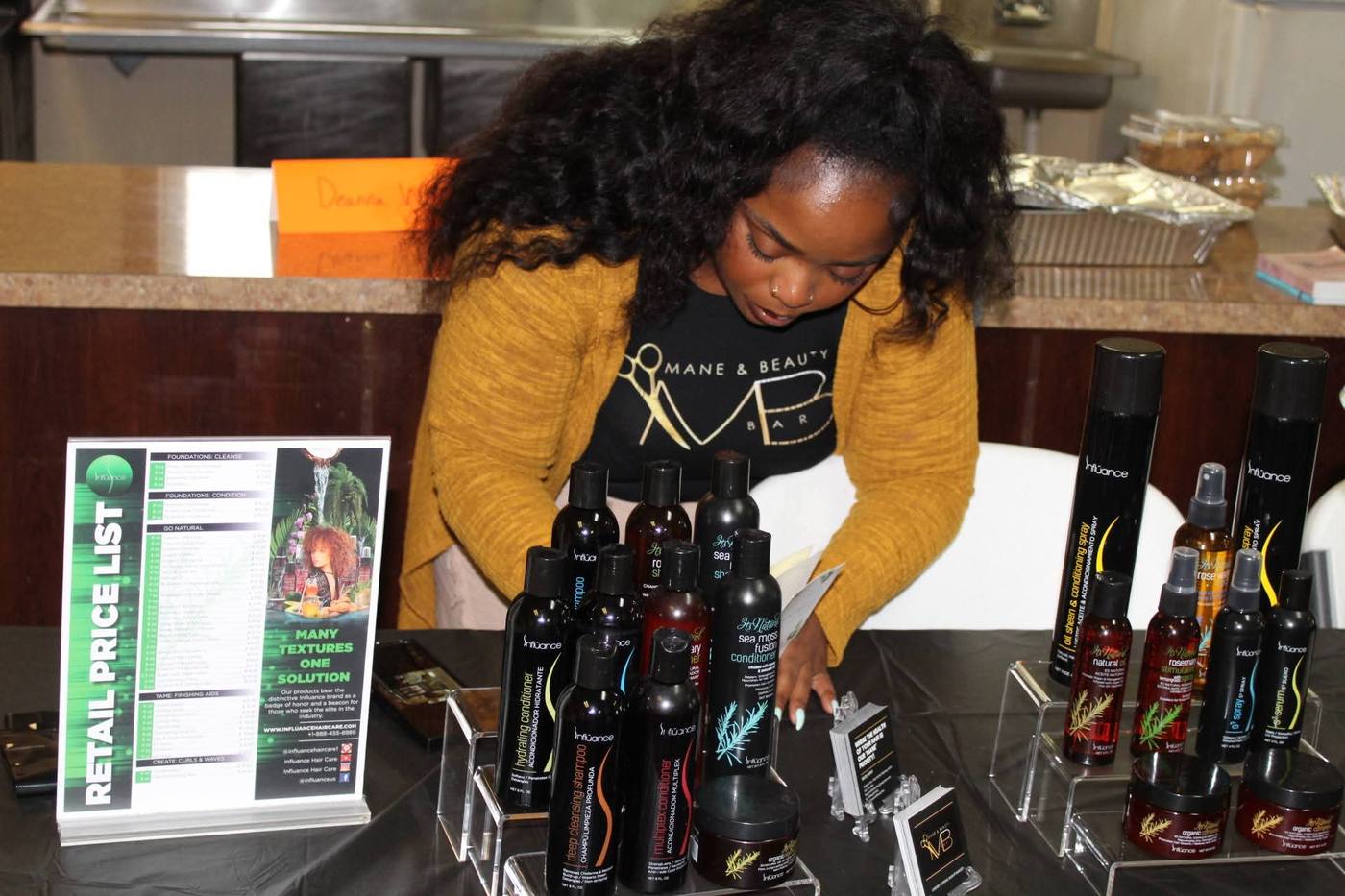 Mane & Beauty Bar vendor arranging Influance hair care products.