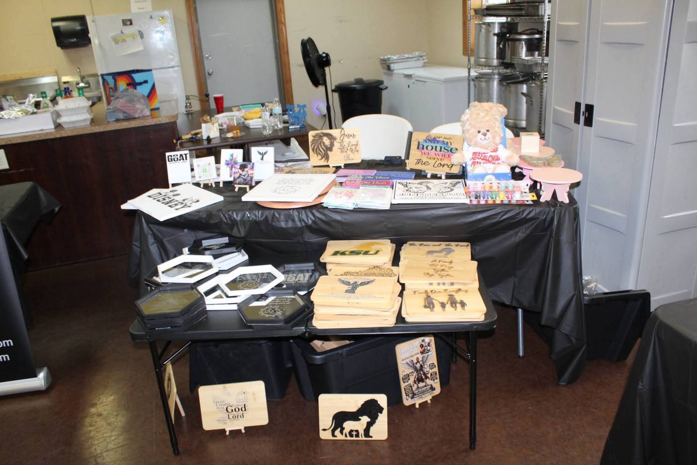 Engraved gifts vendor table with wood signs and Christian-themed pieces.