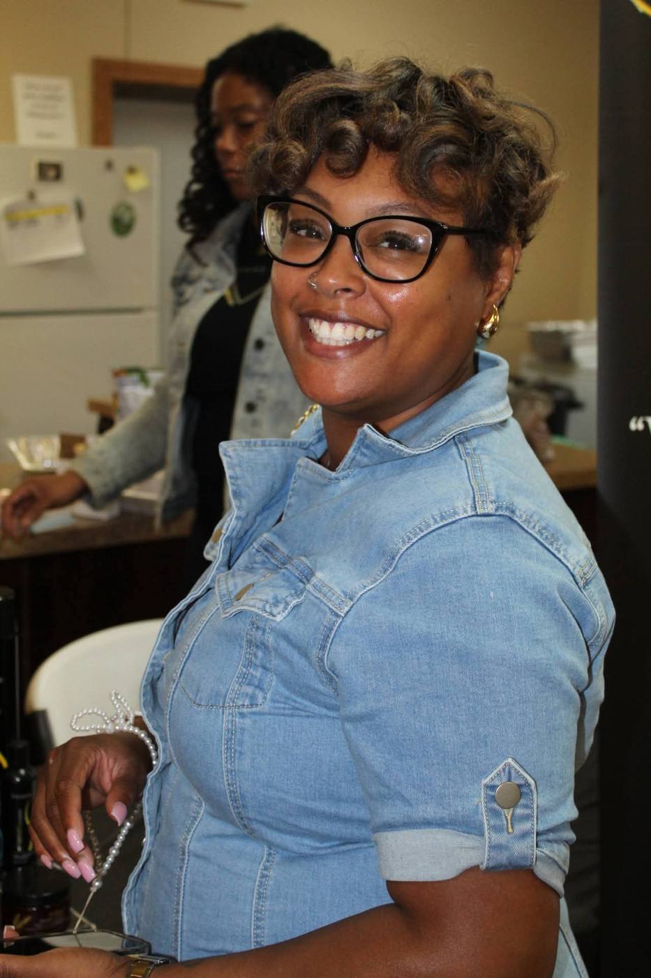 Attendee in a denim shirt smiling at a vendor table.
