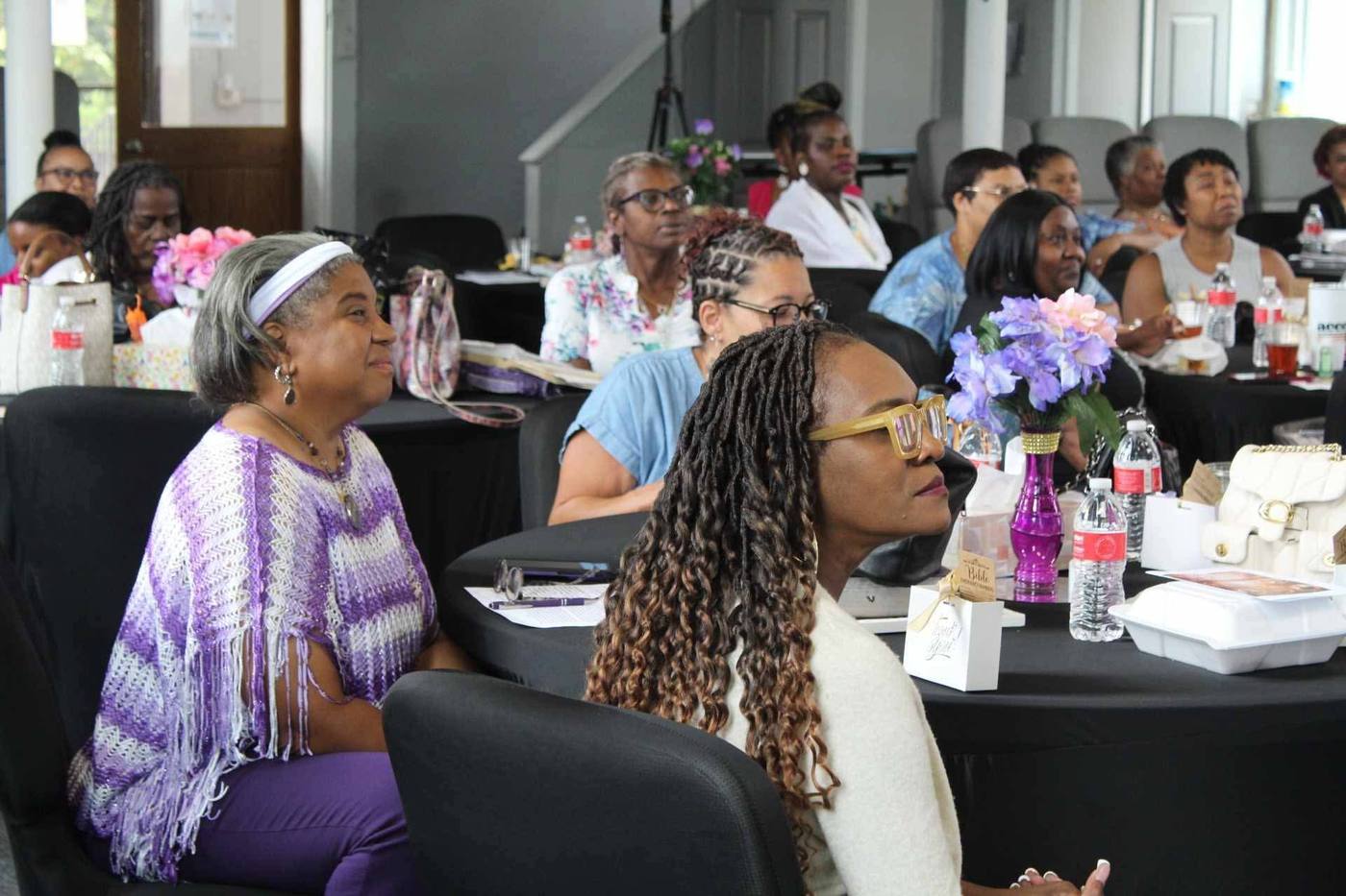 Attendees listening attentively during a session, one in a purple wrap.