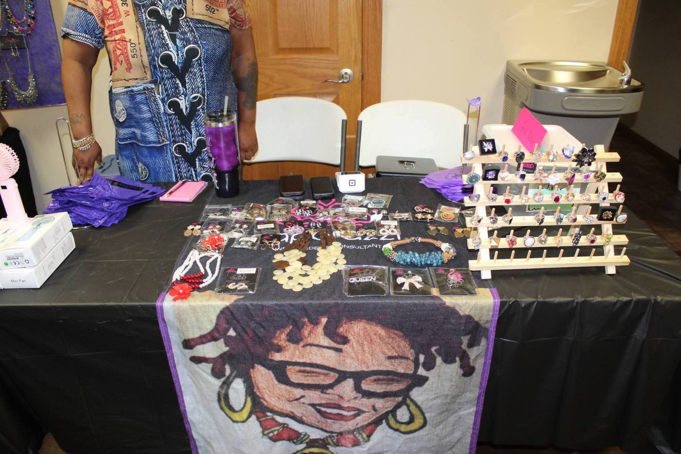 Jewelry vendor table with rings, necklaces, and earrings on display.