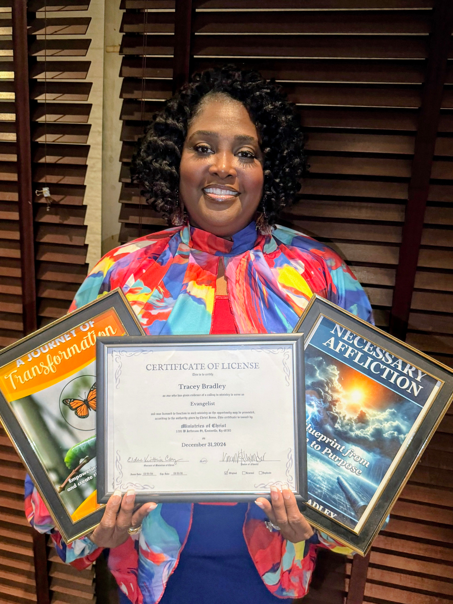 Pastor Tracey holding her ministry license and her two books